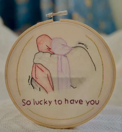Embroidery hoop of two figures hugging